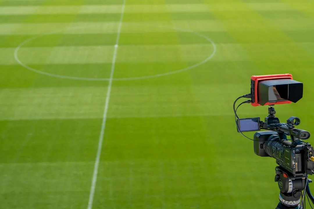 Een sfeerfoto van een camera die het voetbalveld filmt.