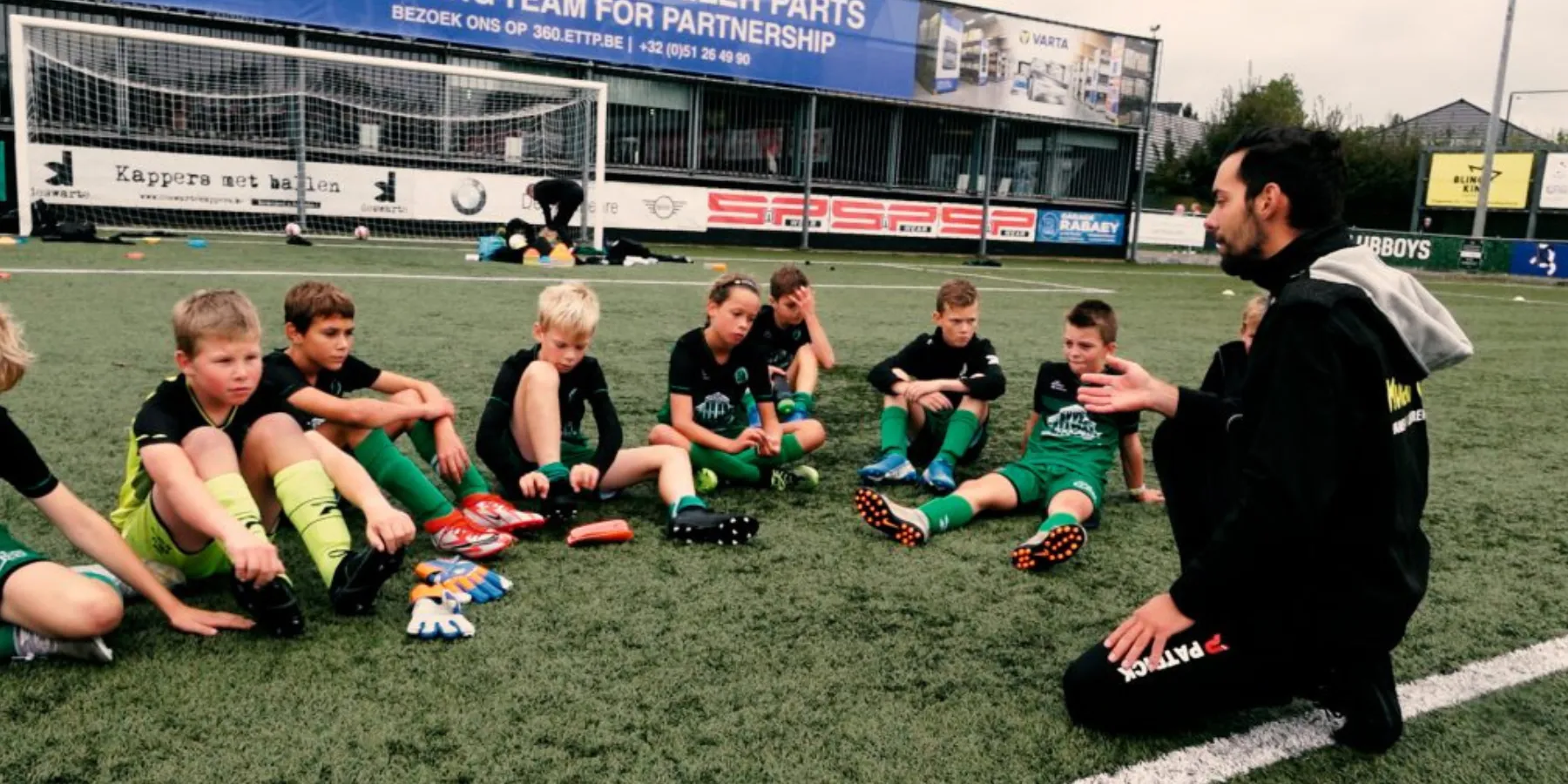 Jeugdtrainer geeft uitleg aan zijn ploeg op het veld